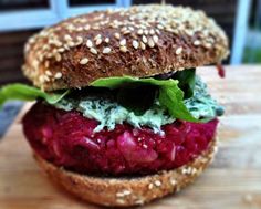 a burger with beets, lettuce and spinach on a sesame seed bun