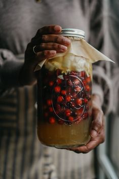 a person holding a jar filled with fruit