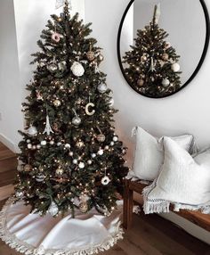 a decorated christmas tree in front of a mirror with ornaments on it and a white throw pillow