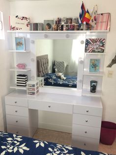 a white desk with a mirror and drawers on top of it next to a bed