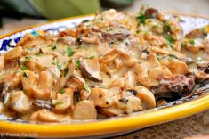 a yellow and blue plate topped with mushrooms covered in gravy on top of a table