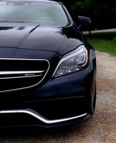 the front end of a black car parked on a gravel road