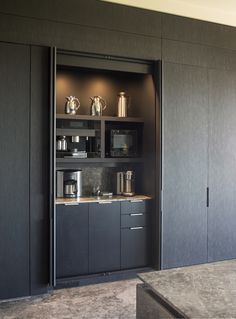 a kitchen with black cabinets and stainless steel appliances in the cupboards that are open