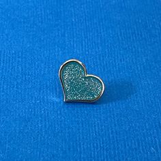 Teal Glitter Heart Enamel Pin - 1/2 inch with Gold MetalAdd some sparkle to your outfit with our Teal Glitter Heart Enamel Pin. This 1/2 inch pin is made from hard enamel with gold metal and features a beautiful teal heart-shaped design with a glittery finish. It also comes with a rubber pinback and a nice pincard, making it the perfect gift for someone special. Order now and add it to your pin collection!*Hard enamel construction — smooth surface design*Approx. 1/2-inch tall*Features one post t Heart-shaped Gold Pins For Gifts, Heart Enamel Pin, Glitter Pin, Gift Wishlist, Pin Card, Rainbow Metal, Orange Glitter, Colorful Accessories, Glitter Hearts