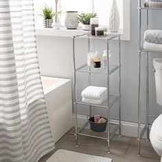 a white toilet sitting next to a bath tub in a bathroom under a window with striped shower curtain