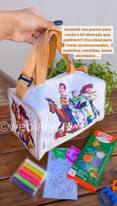 a hand holding onto a bag filled with crayons and other items on a wooden table