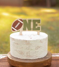 a cake with a football on top and the number one on it sitting on a wooden stand