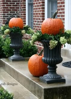 three pumpkins are sitting on top of the planters in front of a building