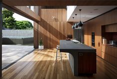 an open kitchen with wooden floors and black counter tops, along with large windows that look out onto the backyard