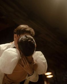 a man and woman embracing each other in front of a stage light with lights on the ceiling