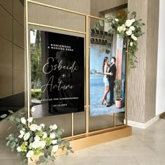 an entrance to a building with flowers in the foreground and a photo on the wall behind it