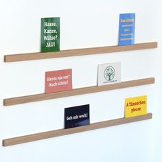 three wooden shelves with different types of books on them, one has an upside down book shelf