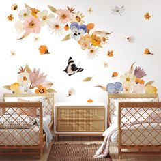 two baby cribs with flowers and butterflies on the wall