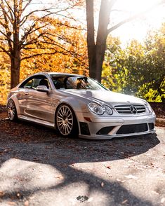 a silver car parked in front of some trees