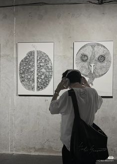 a person standing in front of three pictures on the wall and listening to headphones