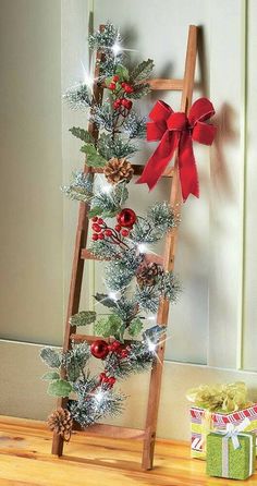 a wooden ladder decorated with christmas decorations and bows, next to a small gift box