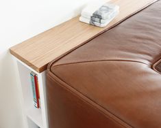 a brown leather couch sitting next to a book shelf with books on it's sides