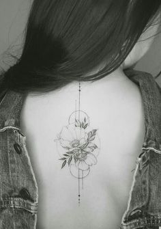 the back of a woman's neck with a flower tattoo on her left side