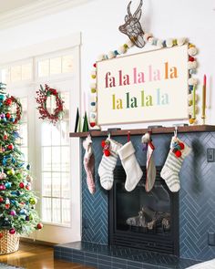 christmas stockings hanging from the mantle in front of a fireplace with a sign that says fala la la la