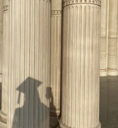 the shadow of a person standing in front of columns