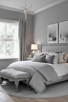 a bedroom with gray walls, white bedding and two pictures on the wall above the bed