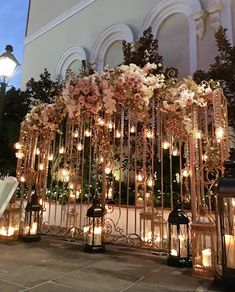 a bunch of lights that are in front of a building with flowers and candles on it