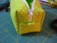 a green and white polka dot purse sitting on top of a table next to scissors