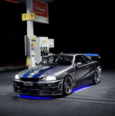 a car parked in front of a gas station at night with blue lights on it