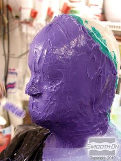 a close up of a person's head covered in purple icing and paint