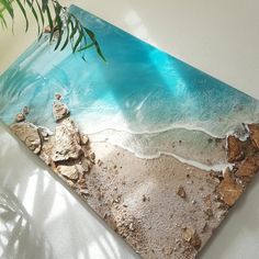 a beach scene with rocks and water on the sand is shown in this acrylic art piece