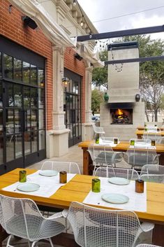 an outdoor dining area with tables, chairs and a fire place in the back ground