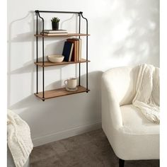 a white chair sitting next to a book shelf with books on it and a potted plant in the corner