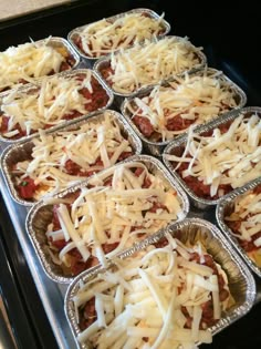 many trays of food with cheese and meat in them sitting on a stove top