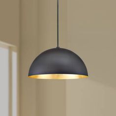 a black and gold colored light hanging from a ceiling fixture in a room with beige walls