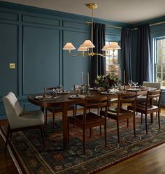 a dining room with blue walls and wooden flooring has a rug on the floor