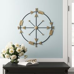 a clock on the wall above a table with flowers and books in front of it