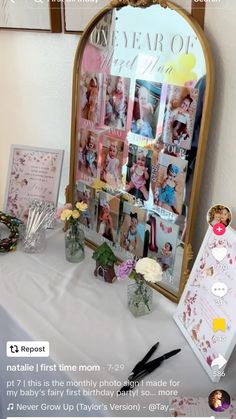 a table topped with pictures and flowers on top of a white table cloth next to a mirror