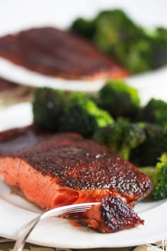 two plates with broccoli and salmon on them, one has a fork in it