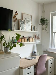 a desk with a laptop computer sitting on top of it next to a potted plant