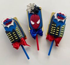 three spiderman lollipops with bows on them sitting next to each other