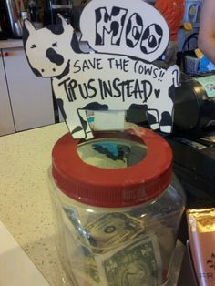 a jar filled with money sitting on top of a counter next to a sign that says save the towns trust instead