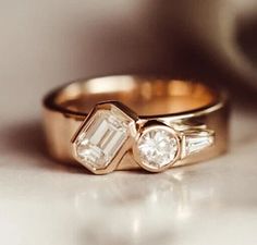 two gold wedding rings with white diamonds on the top and one diamond in the middle