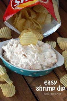 a blue bowl filled with chips next to a bag of potato chips and an easy shrimp dip