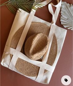 a straw hat sits on top of a white tote bag