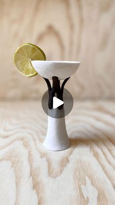 a small white vase with a lemon slice on it