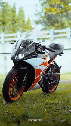 an orange and white motorcycle parked in the grass