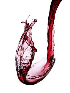 a red liquid splashing out of a wine glass into the shape of a heart