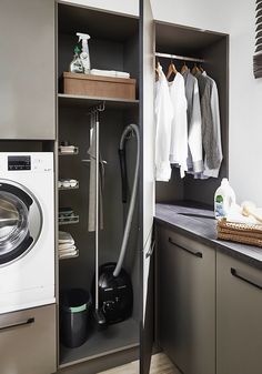 a washer and dryer in a small room next to a shelf with clothes on it