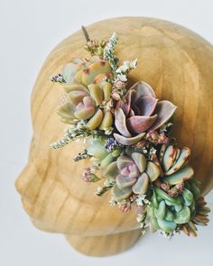 a wooden head with succulents and flowers on it