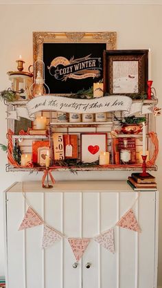 a shelf with candles, pictures and other items on it in front of a wall